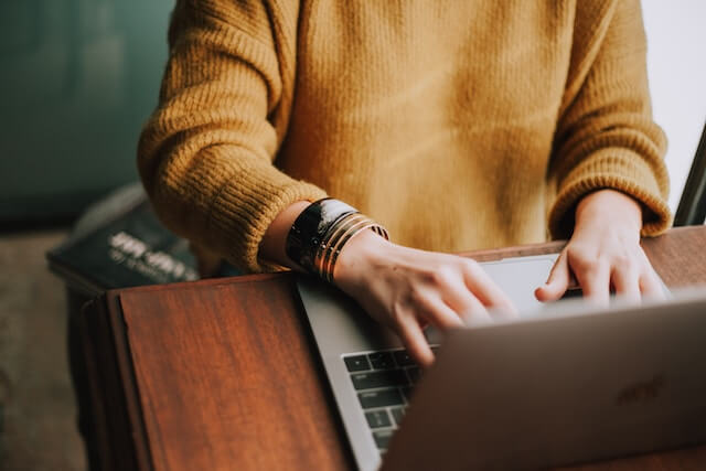 Woman with brown sweater using a laptop to contact a company.